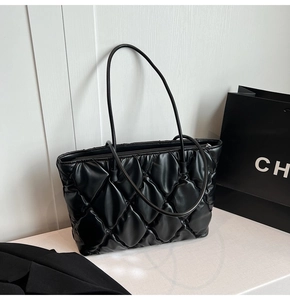 Close-up of black quilted tote bag texture featuring diamond stitching and fine straps