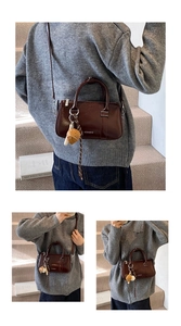 Détail du sac polochon en cuir ciré marron avec pendentif cœur tressé et poignées