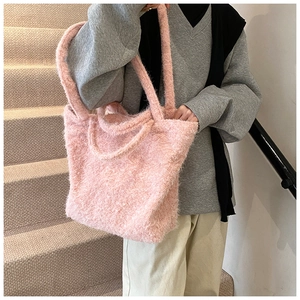 Gros plan d'un sac cabas rose en peluche à texture longue sur l'épaule d'un modèle