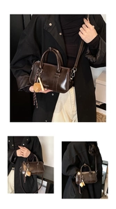 Détail du sac polochon en cuir ciré marron foncé avec un joli pendentif en fraise