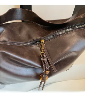 Macro detail of the smooth metal zipper and braided rope puller on the brown leather tote