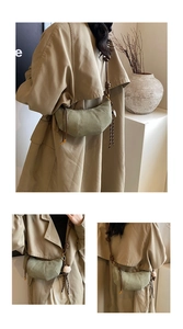 Detail of dark green suede croissant bag with rope strap and fuzzy ball charm
