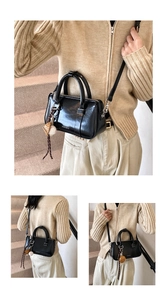 Détail du sac Boston en cuir ciré noir avec charm baseball et bandoulière réglable