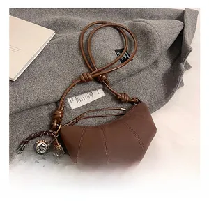 Close-up of brown matte dumpling bag with knotted strap and creative charm details