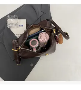 Top view of spacious brown leather tote interior holding umbrella, bottle and wallet