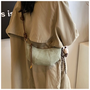 Detail of light green crescent bag with matte texture and knotted brown leather strap