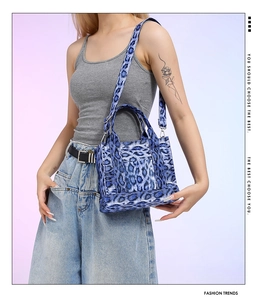 Close-up of a blue leopard print tote bag with dual handles and metal strap buckles