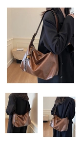 Close-up of dark brown leather texture and decorative tassel on large hobo bag