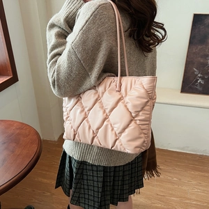 Pink quilted tote bag with diamond stitching shown on shoulder in a lifestyle setting