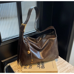 Detail of deep brown faux leather hobo tote with wide strap and gold buckle