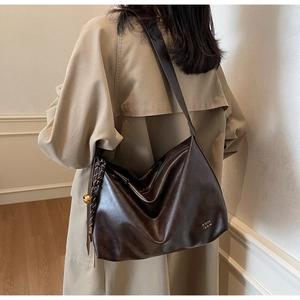 Détail de ce sac fourre-tout marron foncé avec logo et pendentif boule dorée