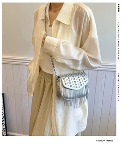 Detail of silver crossbody bag with sparkling rhinestones, metal tassels and chain strap