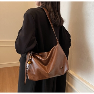 Detail of vintage brown leather hobo bag with a decorative metal ball charm and wide strap