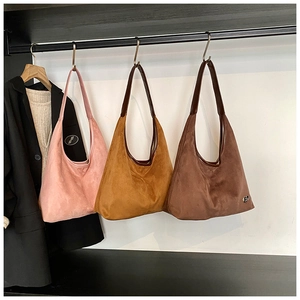 Close-up of hobo shoulder bags in pink, ginger and brown suede with leather straps