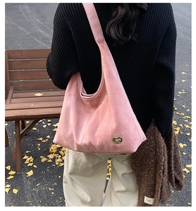 Pink suede tote bag with heart metal plaque shown in an outdoor autumn setting