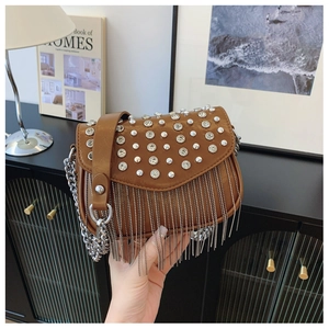 Detail view of brown leather crossbody bag with rhinestones, rivets and silver tassels