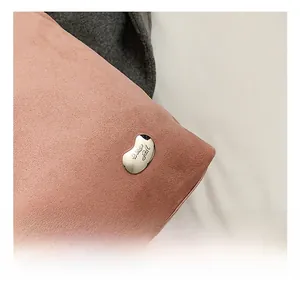 Detail of silver bean-shaped metal hardware with fine engraving on pink suede bag