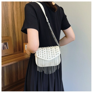 Detail of white crossbody bag with silver studs, metal fringe, and chain strap for women