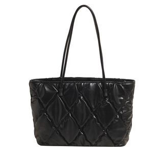 Chic black quilted tote bag with padded rhombus stitching and slim top handles on white background