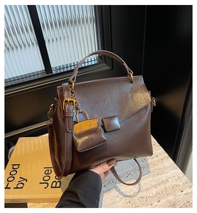 Macro detail of dark brown leather handbag with vintage gold buckle and mini bag charm