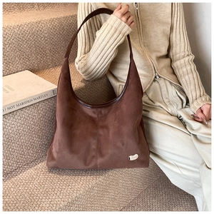 Detail of dark brown suede tote bag with leather piping and silver pebble metal charm