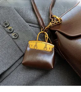 Close-up of a coffee brown mini bag charm with lychee texture and gold metal handle