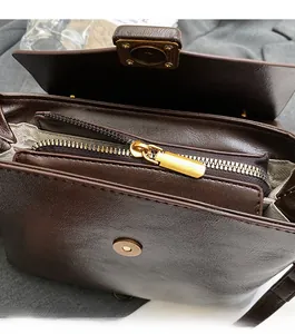 Detail view of smooth golden metal zipper and magnetic closure on dark brown leather bag