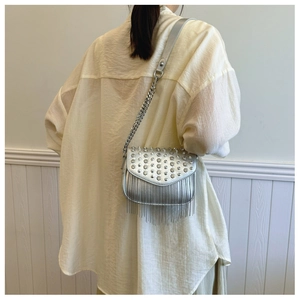 Detail of silver crossbody bag featuring rhinestone studs and long metallic fringe tassels