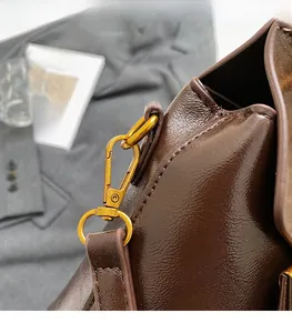 Close-up of vintage brown leather bag with glossy finish and textured gold hardware