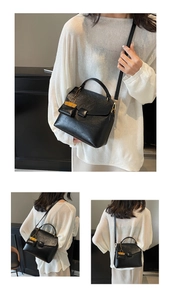 Detail of black vintage crossbody bag with top handle and yellow mini pendant charm