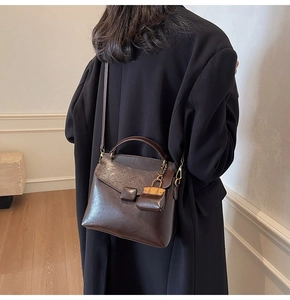 Close-up of a dark brown vintage faux leather handbag with adjustable shoulder strap