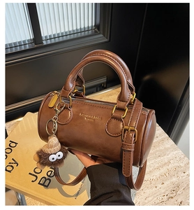 Detail of vintage brown cylinder handbag with golden hardware and plush charm