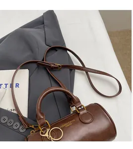 Detailed top view of a brown cylinder Boston bag with gold hardware and shoulder strap