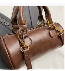 Close-up of vintage brown cylindrical bag featuring high-quality bronze hardware details