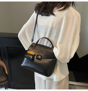 Detail of black pebbled leather handbag with a contrasting yellow mini bag charm
