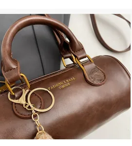 Macro detail of dark brown barrel bag with golden hardware and textured wax leather