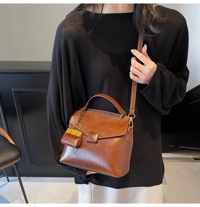 Close-up of brown faux leather crossbody bag with adjustable strap and mini charm