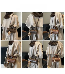 Retro brown cylinder shoulder bag with glossy leather texture and cute plush charm detail