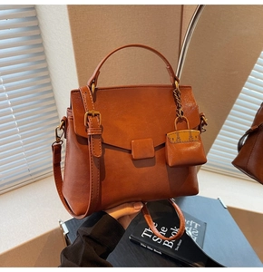 Detail of vintage brown leather handbag with mini charm and bronze hardware