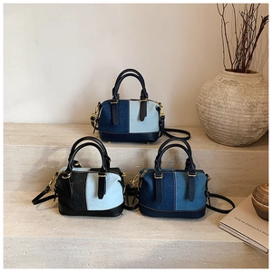 Three denim patchwork boston bags in different blue tones displayed on stone steps