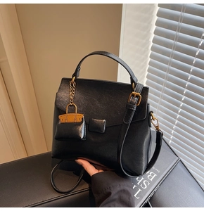 Macro detail of the vintage black leather texture and gold metal buckle on a shoulder bag