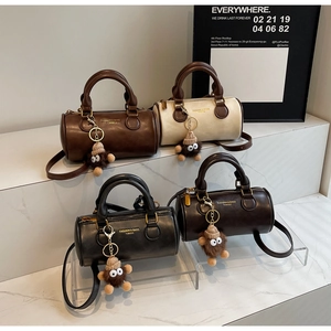Detail of four cylinder Boston bags with plush charms and detachable straps on acrylic stands