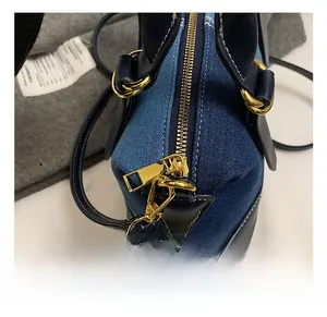 Detailed close-up of blue denim and leather stitching with polished gold-tone hardware