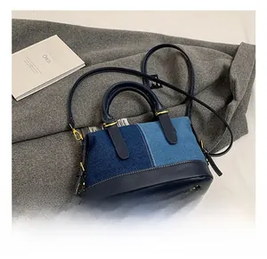 Detail view of denim patchwork Boston bag with gold hardware and leather handles