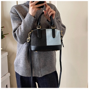 Detail of denim patchwork Boston bag featuring black leather trim and gold-tone hardware