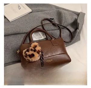 Détail du sac Boston marron foncé avec breloque cœur léopard sur un manteau gris