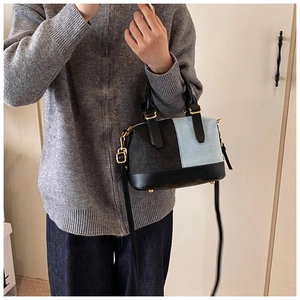 Detail of color-block denim Boston bag with black leather straps and gold hardware