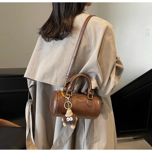 Close-up of a retro brown cylindrical handbag with a cute plush doll charm detail