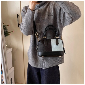 Detail of Boston bag with black wool and denim patchwork and adjustable gold buckle strap