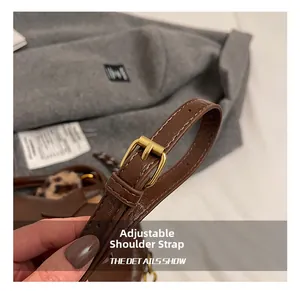 Détail macro de la bandoulière réglable en cuir marron avec boucle en métal doré